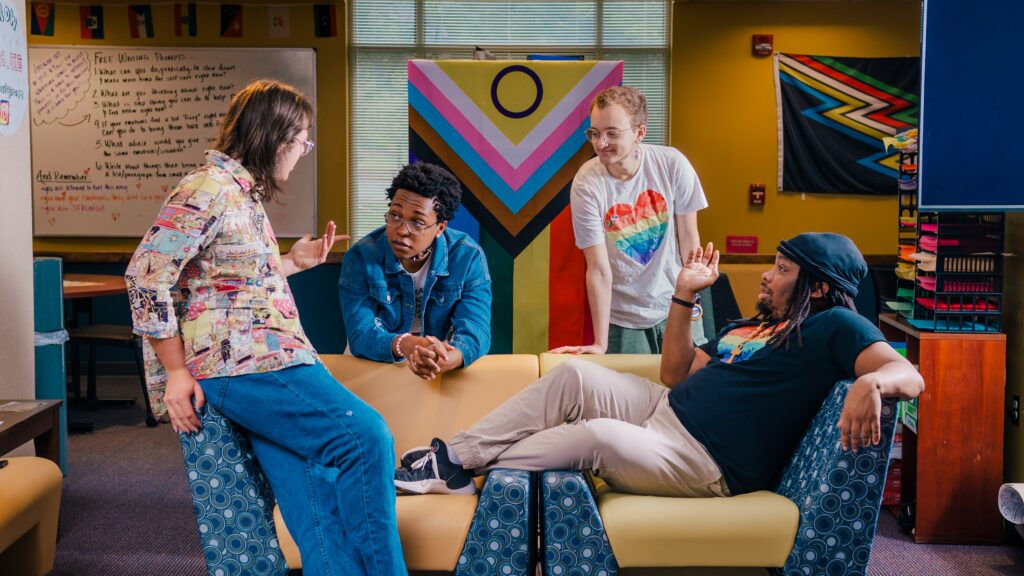 A group of diverse students sitting on a couch having a conversation.